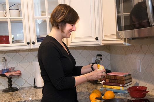 Marissa Nicosia, food historian behind Cooking in the Archives, zesting citrus beside a stack of historic cookbooks