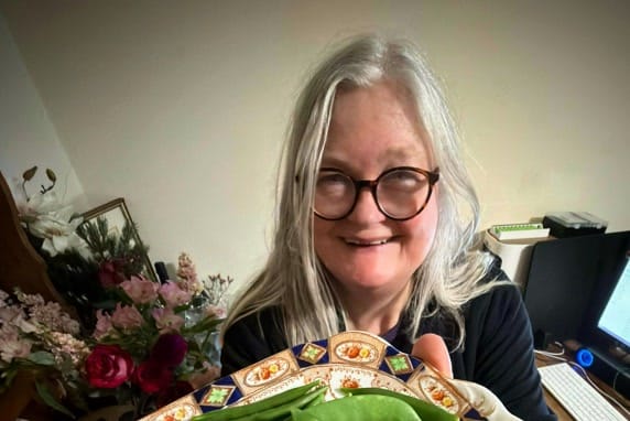 Carolyn Ekins of The 1940s Experiment smiling at home over a plate of wartime homity pie and sugar snap peas